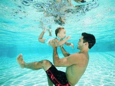 Father Swimming Underwater With Daughter In Swimming Pool Stock Photo