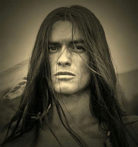 A Man With Long Hair Is Staring At The Camera While He Has Long Hair On