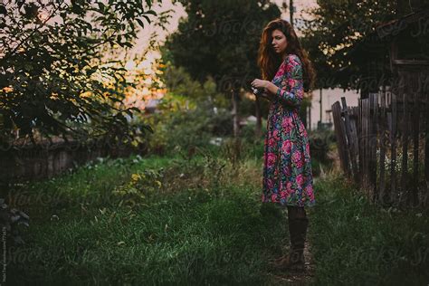 Beautiful Young Woman In Floral Dress With Camera In The Garden By