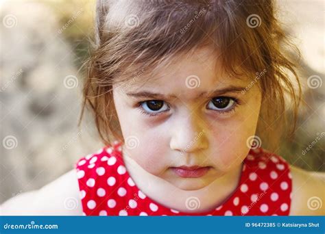 Portrait Of Cute Sad Little Girl Looking At Camera At Summer Day Stock