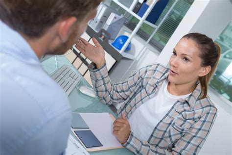 Customer And Female Financial Agent In Discussion At Desk Stock Photo
