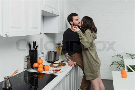 Beautiful Young Romantic Couple Kissing During Breakfast In Kitchen