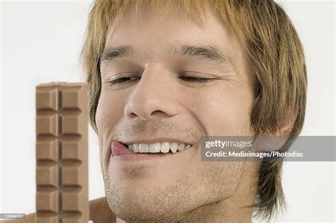 Young Man Licking His Lips And Looking At Chocolate Candy Bar High Res