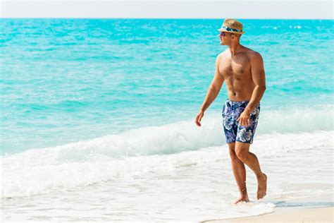 Handsome Caucasian Man In Swimsuit Sunbathing On Beach In Summer Stock