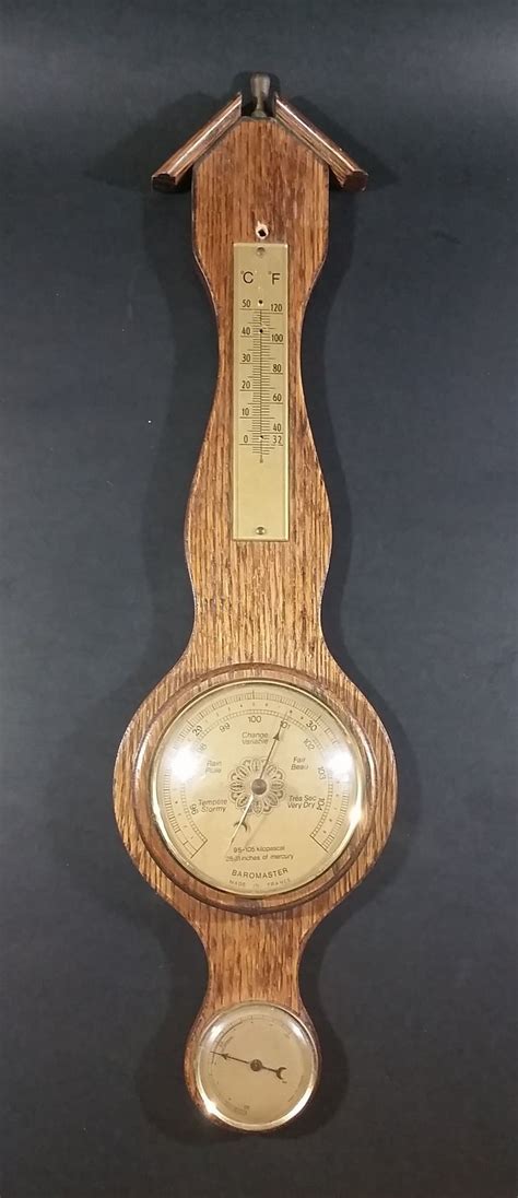 An Old Wooden Clock With Thermometer Attached To Its Back Side On A