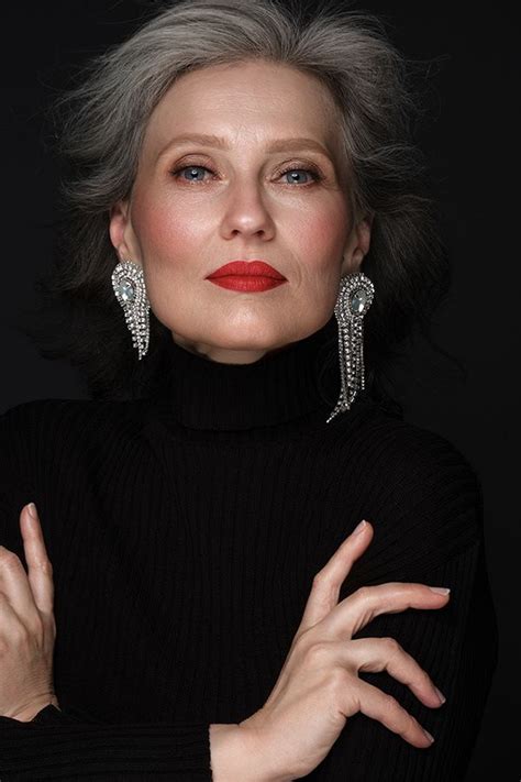 an older woman with grey hair and red lipstick posing for a photo in front of a black background