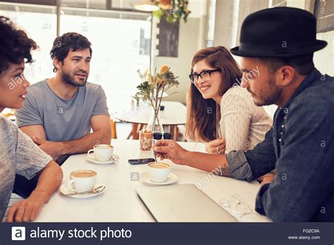 Grupo De Jóvenes Amigos Sentados Y Hablando En Una Cafetería Los