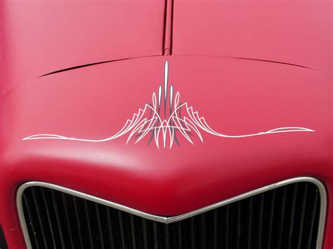 The Front End Of An Old Red Car With White Lines On Its Hood