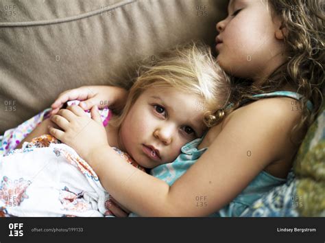 Two Little Girls Cuddling On Couch Stock Photo Offset