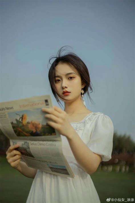 A Woman In White Dress Reading A Newspaper