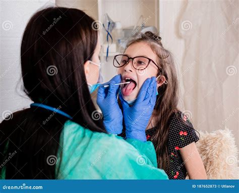 A Female Doctor Carefully Examines The Throat Of A Small Patient And Takes A Smear Of Mucosa For