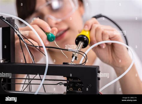 Young Female Technician Wearing Safety Eyeglasses Using Soldering Iron