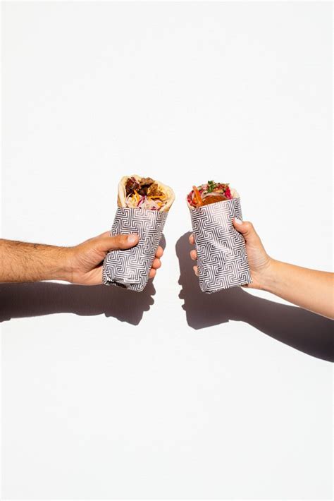 Two People Holding Food In Their Hands Against A White Background