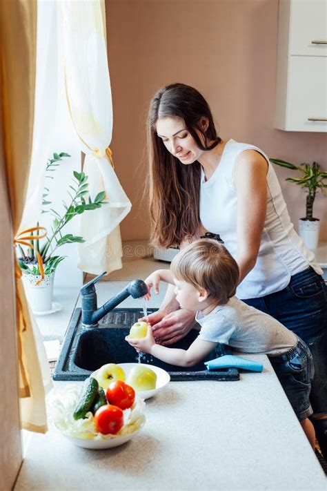 El Niño Pequeño Está Ayudando A La Mamá En La Cocina Foto De Archivo