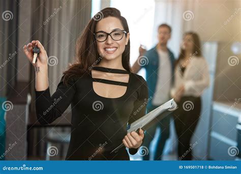 Attractive Smiling Woman Realtor Property Manager With Keys In One Hand And Documents In Anither