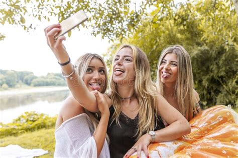 Female Millennial Girlfriends Taking A Selfie Outdoors On The River