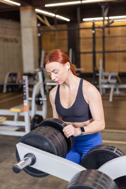 Premium Photo Fit Woman Holding Barbell Disk In Gym