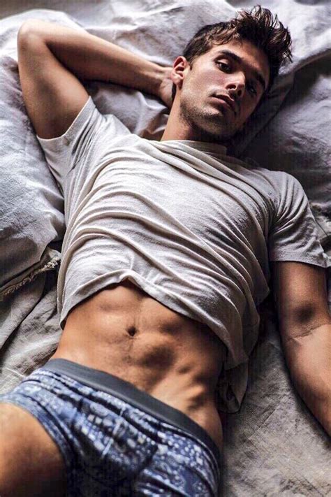 A Man Laying On Top Of A Bed Under A White Blanket With His Shirt Open