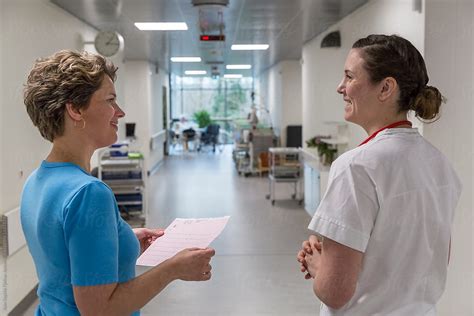 Two Nurses Talking In A Hallway By Stocksy Contributor Bowery Image
