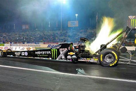 A Monster Truck With Flames Coming Out Of Its Tires On A Race Track