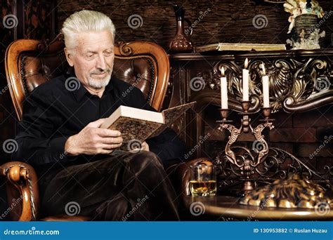Portrait Of Senior Man Reading Book While Sitting Stock Photo Image