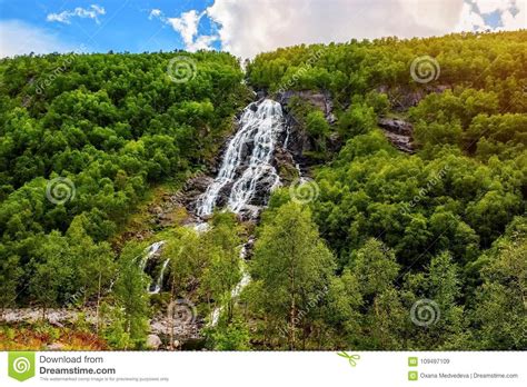 Mountain Landscape With A Beautiful Waterfall And Cloudy Sky The