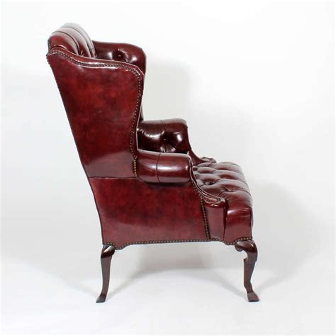 Back legs are subtlely carved with a dramatic rake. Pair of Red Leather Tufted Wing Chairs at 1stDibs