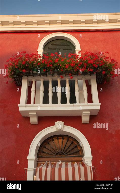 Italy Burano Red Buildings And Geraniums On Balcony Stock Photo Alamy