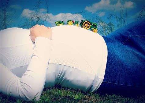 A Woman Laying On The Grass With A Toy Tractor In Her Lap And Head Resting On Her Stomach