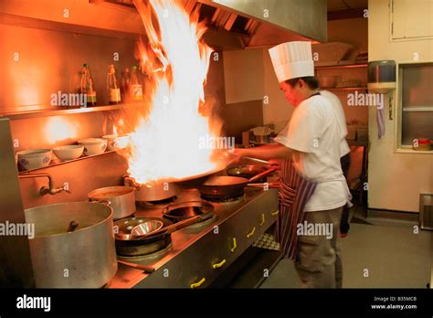 Male Thai Chef Cooking With Flaming Wok In A Restaurant Kitchen