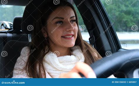 cheerful female with a joyful positive facial expression sitting in the driver seat in a car