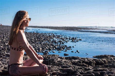Caucasian Woman Sitting On Beach Wearing Bikini Stock Photo Dissolve