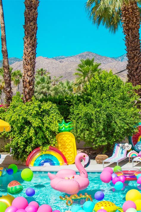 Flamingos Float Around In The Pool Surrounded By Palm Trees And Lawn Chairs With Balloons