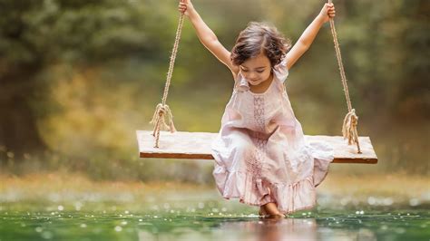 Cute Little Girl Is Wearing Light Peach Dress Riding On Swing Over