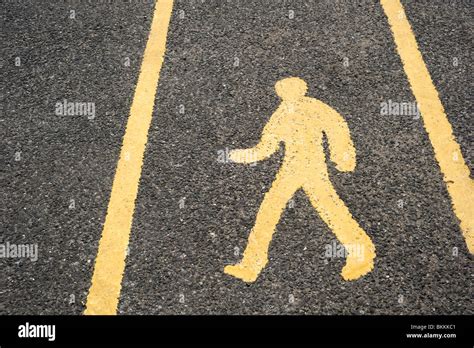 Yellow Pedestrian Walkway Sign Painted On A Tarmac Road Surface In A