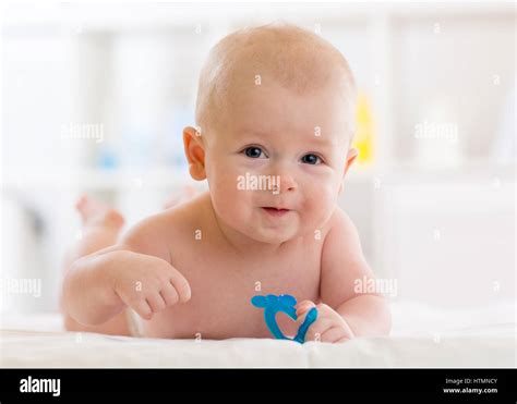 Portrait Of Adorable Baby Kid Boy Lying On His Stomach And Holding