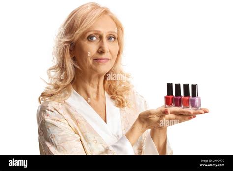 beautiful mature woman in a bathrobe holding nail polishes isolated on white background stock