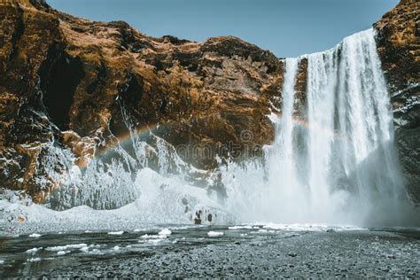 Skogafoss Waterfall In Iceland With Rainbow On A Sunny Day With Blue