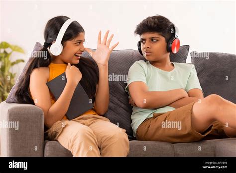 Young Sister Teasing Her Brother While Sitting On Sofa With Digital Tabletin Living Room Stock