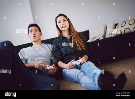 Young Couple Playing Video Games Together While Sitting In Their Living
