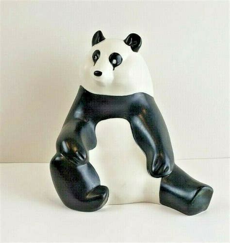 A Black And White Panda Bear Figurine Sitting On Top Of Its Legs