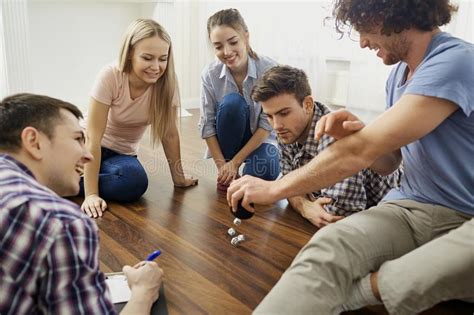 A Group Of Friends Play Board Games On The Floor Indoors Stock Image