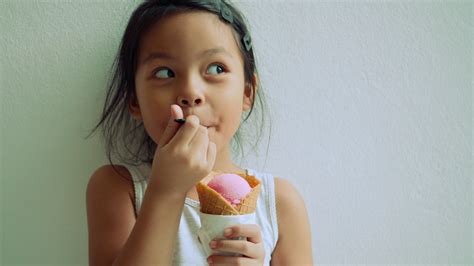 Little Girl Standing Eating Ice Cream And Showing Very Happy Face