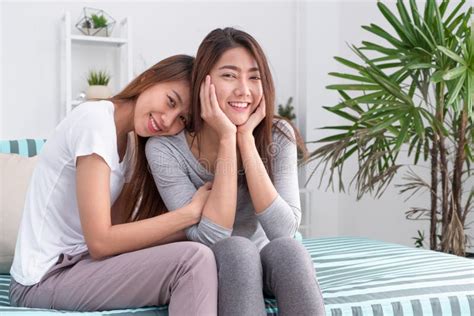 Two Asia Woman Hug Each Another And Sitting On Sofa In Living Room At