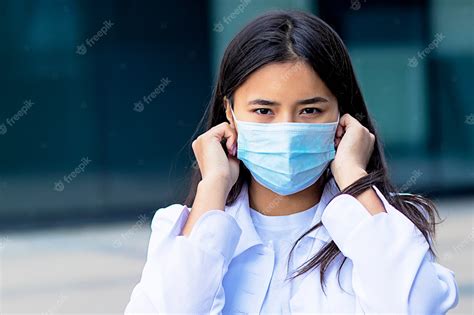 premium photo asian woman attractive ethnic girl wearing a medical mask on her face looking