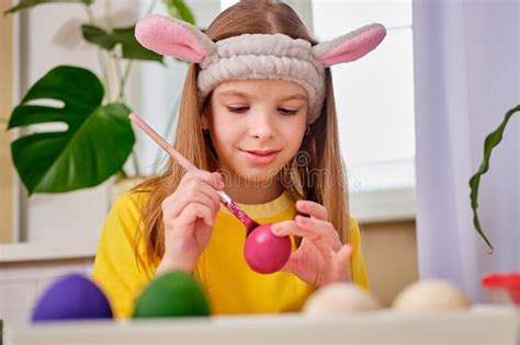 A Girl Paints Easter Eggs With Paints Portrait Of Caucasian Girl