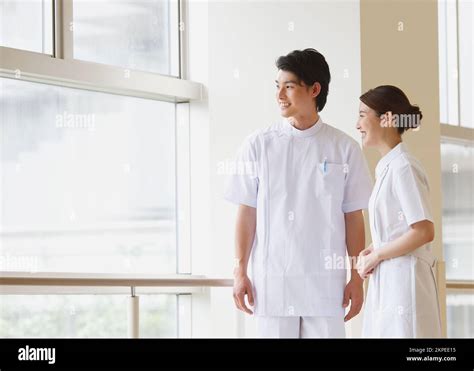 Smiling Young Japanese Nurse Having A Conversation In The Hallway Stock