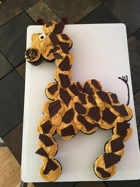 A Cake Shaped Like A Giraffe Sitting On Top Of A White Table Next To A