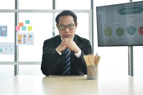 Serious Asian Business Man Boss Sitting At Desk In Office Meeting Room
