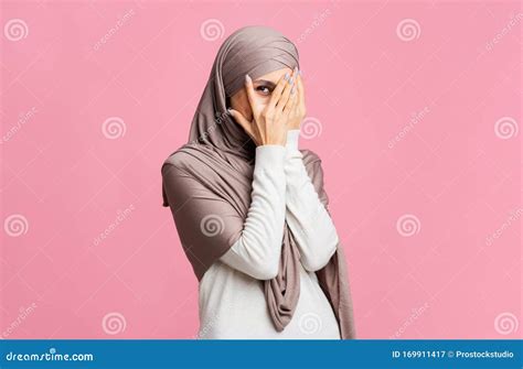 shy arabic woman in hijab peeking through fingers with interest stock image image of covering